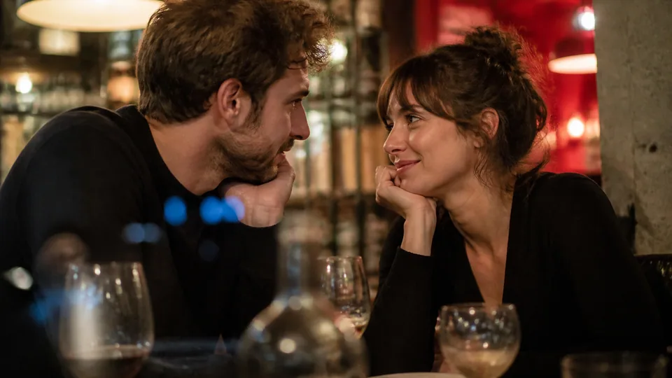 Couple échangeant un regard complice pendant une soirée