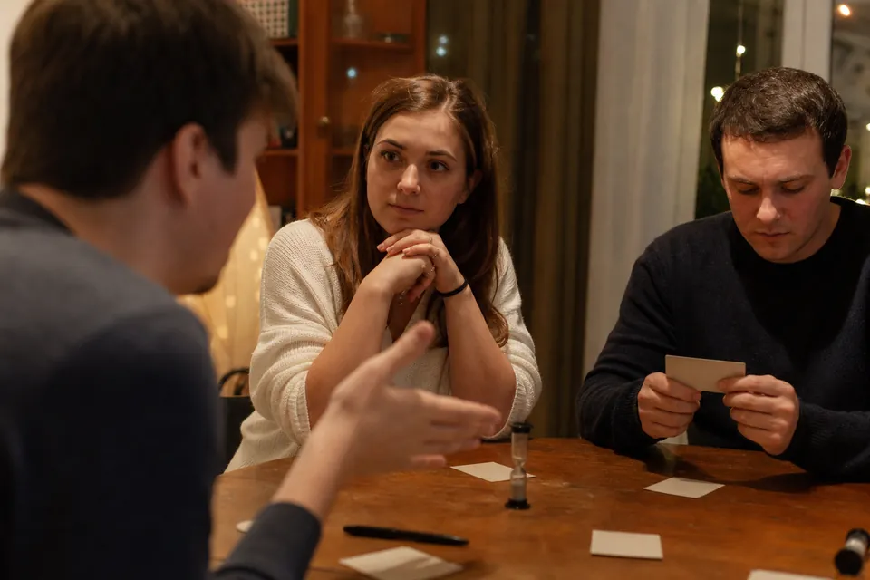 Friends privately checking a clue card before an impostor word game