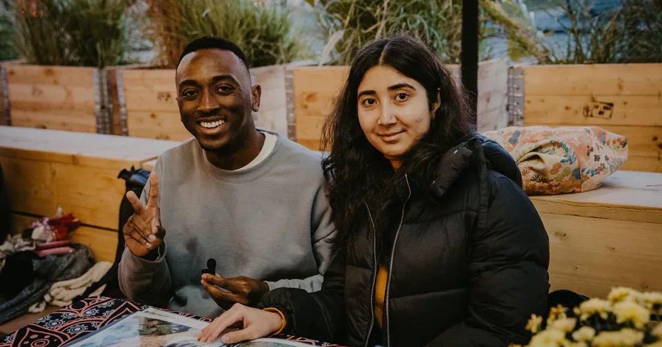 Zwei Freunde sitzen in einem Berliner Café und lächeln