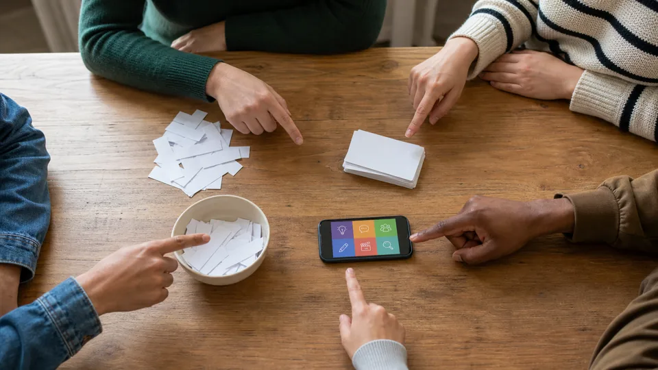 Friends choosing between paper, cards, and a phone game