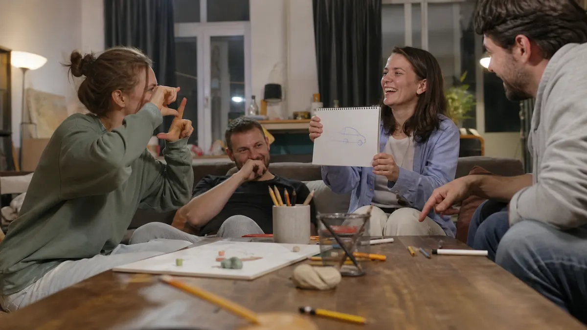 Friends laughing while one player shows a simple car drawing