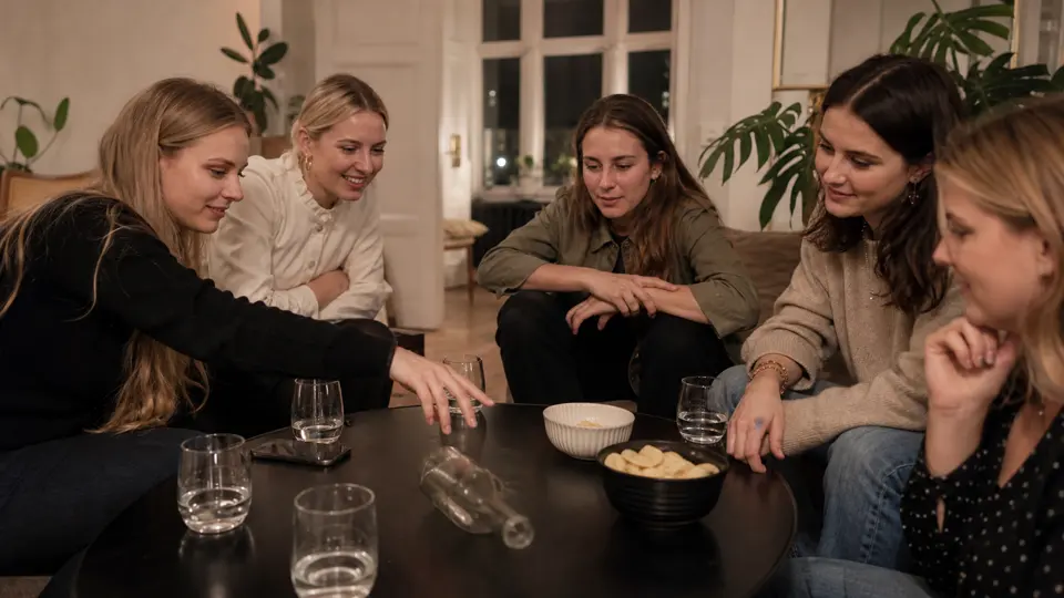 Veninder spiller en spørgeleg rundt om sofabordet