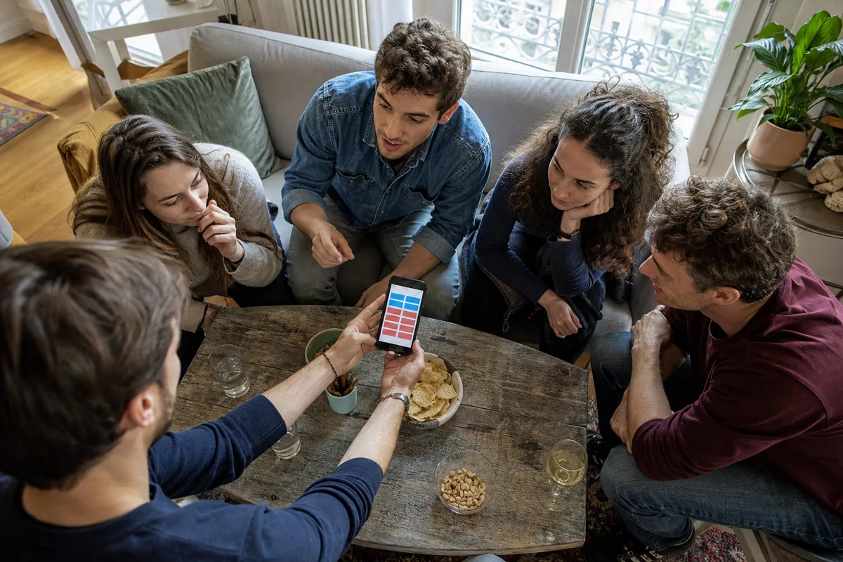 Amis jouant au jeu Tabou avec un téléphone posé sur la table
