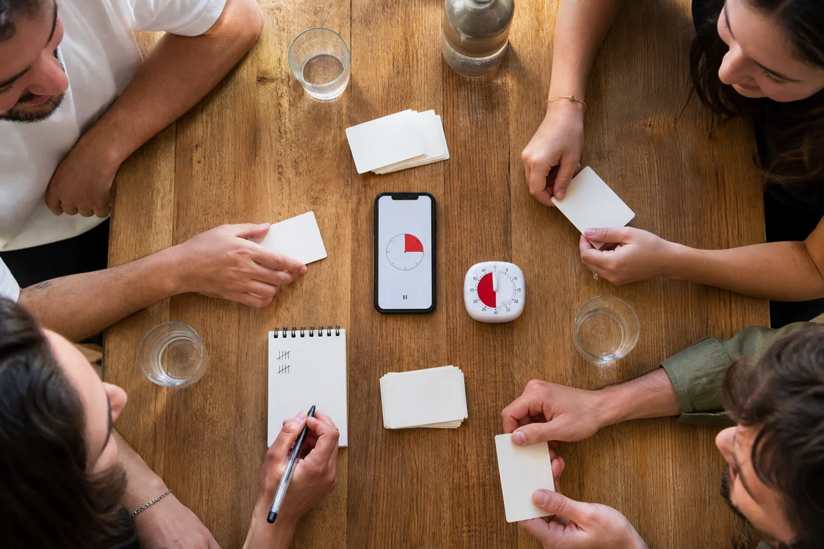 Deux équipes préparent un minuteur et une feuille de score pour Taboo