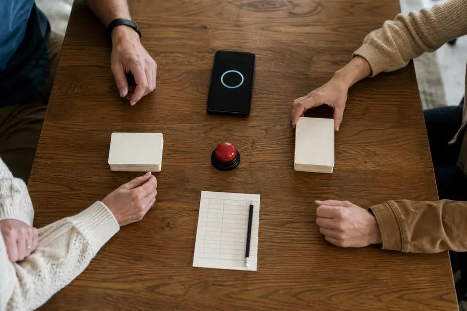 Two card stacks, a phone timer, score sheet, and red buzzer ready for a Taboo game