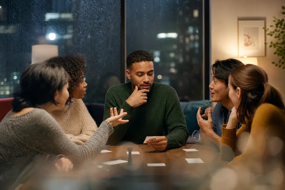Clue-giver thinking while friends offer guesses around a game table