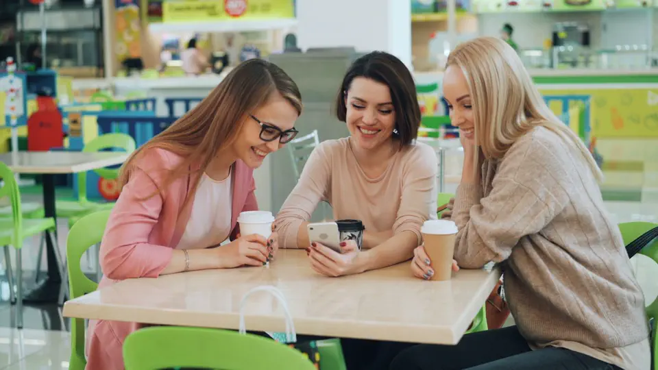 Drei Freunde lachen gemeinsam über Fragen auf einem Handy