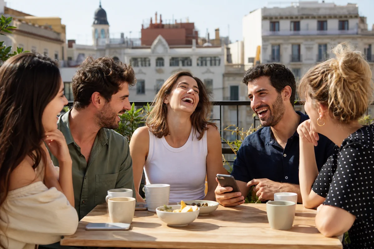 Grupo de amigos charlando y riendo en una terraza durante un juego de preguntas