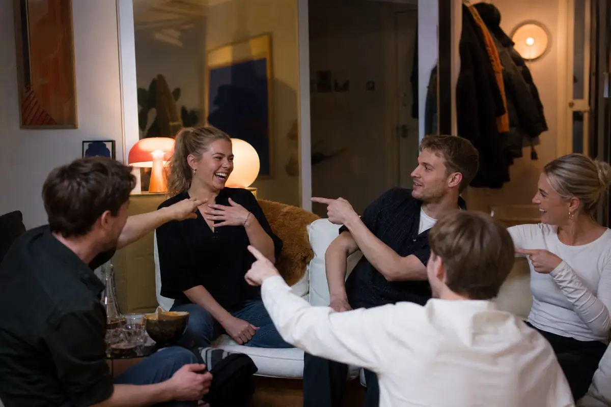 Vänner skrattar och pekar i ett frågespel